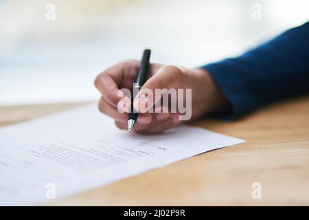 Apporre un segno sulla linea tratteggiata. Scatto di una persona che firma i documenti. Foto Stock