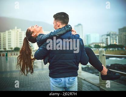 Lascia che l'amore ti porti via. Scatto di un giovane uomo che porta romanticamente la sua ragazza all'aperto. Foto Stock