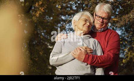 Ritratto di anziana coppia caucasica donna guardando il marito, uomo guardando giù coprendo la mano di sua moglie con il suo ritratto copia spazio fuoco selettivo . Foto di alta qualità Foto Stock