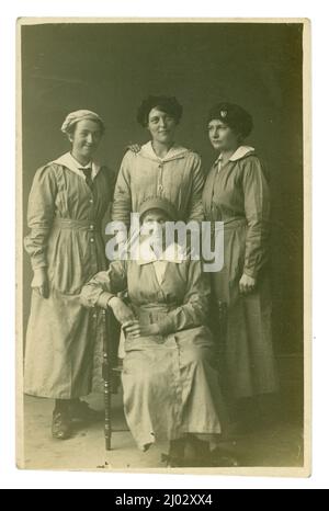 Cartolina originale dell'era WW1 di 4 lavoratori di donne, possibilmente operai di munizioni, operai di fabbrica, 2 stanno portando lo stesso marchio di cappello (ma non è il distintivo usuale 'di servizio di guerra 'indossato da molti operai di munizioni), circa 1916, U.K. Foto Stock