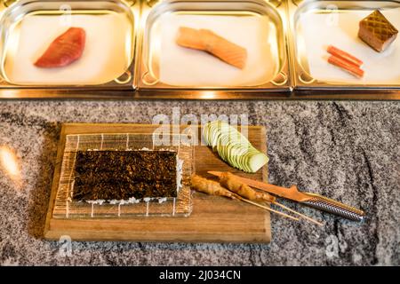 Immagine ravvicinata del tavolo di lavoro al sushi bar con ingredienti di sushi pronti per preparare il pasto. Foto Stock