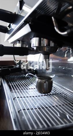 tempo congelato di un gatto di caffè in una tazza servita da una macchina all'interno di un deposito caffè in messico Foto Stock