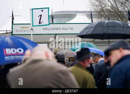 I Racegoers prendono rifugio sotto gli ombrelloni mentre si accodano davanti all'entrata il giorno due del festival di Cheltenham all'ippodromo di Cheltenham. Data foto: Mercoledì 16 marzo 2022. Foto Stock