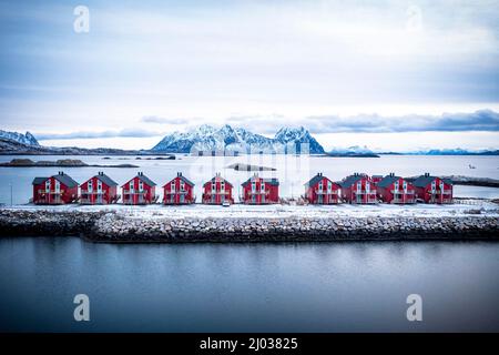 Vista aerea delle cabine rosse di rorbu in fila tra il mare freddo in inverno, Svolvaer, contea di Nordland, Isole Lofoten, Norvegia, Scandinavia, Europa Foto Stock