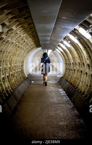 Donna che cammina attraverso il tunnel del piede di Greenwich, Greenwich, Londra, Inghilterra, Regno Unito, Europa Foto Stock