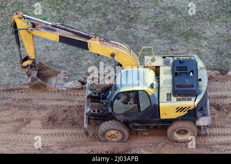 Una pala caricatrice gommata scava il terreno in un cantiere per spianare una strada Foto Stock