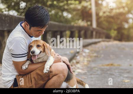 La gente ama e cura il suo cane da compagnia. Vecchio cane Beagle stare con l'uomo. Foto Stock
