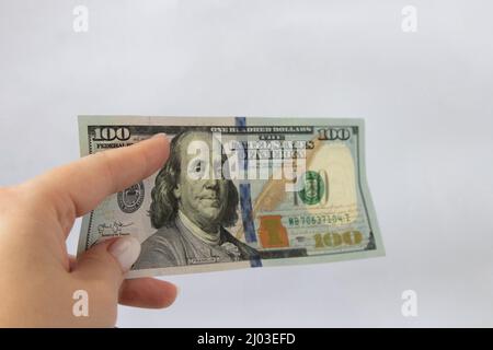 100 dollari in mano primo piano su uno sfondo bianco isolato. Un conto di cento dollari Foto Stock