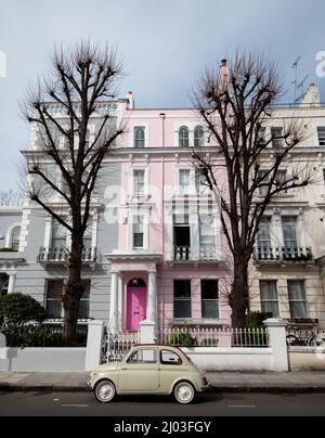 Auto classica Fiat 500 di colore beige, parcheggiata di fronte a una casa con una porta rosa su una strada residenziale a Notting Hill, Londra ovest Regno Unito. Foto Stock