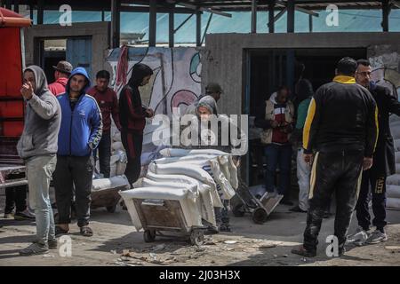 Città di Gaza, territori palestinesi. 16th Mar 2022. I palestinesi raccolgono aiuti alimentari da un centro di distribuzione gestito dall'Agenzia delle Nazioni Unite per il soccorso e l'occupazione (UNRWA). I prezzi dei prodotti alimentari a Gaza City sono saliti dopo l'invasione russa dell'Ucraina. Alcuni rifugiati vendono l'aiuto alimentare, che comprende farina, olio da cucina, riso, lenticchie e latte; per garantire i soldi per la loro vita. Credit: Mohammed Talatene/dpa/Alamy Live News Foto Stock