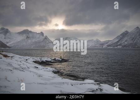 Paesaggio invernale mozzafiato con il ghiaccio del mare norvegese al tramonto. Montagne glaciali intorno al villaggio di Husoy, nel nord della Norvegia. Individuazione di SCA Foto Stock