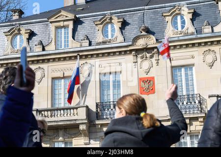 Strasburgo, Francia - 6 marzo 2022: Vista posteriore della donna che sventola bandiera della Georgia di fronte al Consolato russo in solidarietà con gli ucraini e contro la guerra dopo l'invasione russa Foto Stock