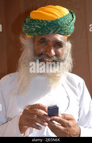 Jodhpur; Rajasthan; India; Asia; Oct, 07, 2006 - Rajasthani rajput uomo di barba bianca utilizzando il telefono cellulare in abito tradizionale Foto Stock