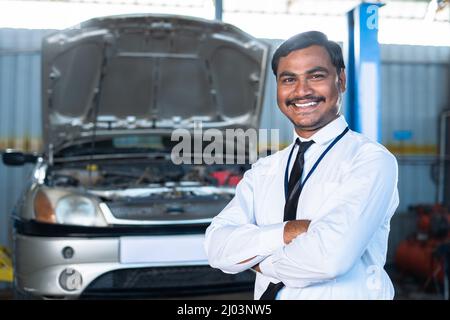 Responsabile o supervisore fiducioso al garage auto in piedi con le braccia incrociate guardando la fotocamera - concPET di successo occupazione, carriera e. Foto Stock