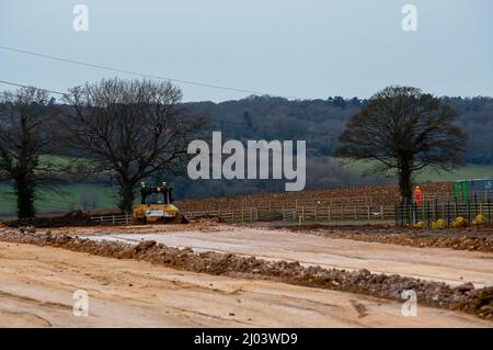 Wendover, Aylesbury, Regno Unito. 15th marzo 2022. HS2 stanno costruendo un'altra strada di trasporto per i loro autocarri attraverso l'ex terreno agricolo a Little Hunts Green Farm e Grim's Ditch un antico monumento programmato, parte del quale è stato distrutto entro il HS2. Un enorme viadotto sarà costruito entro il HS2 da dove il treno uscirà dal tunnel al Portale Nord a South Heath, Great Missenden attraverso la valle attraverso Wendover. La controversa costruzione della ferrovia ad alta velocità del HS2 da Londra a Birmingham è già ampiamente in eccesso di budget. Credit: Maureen McLean/Alamy Foto Stock