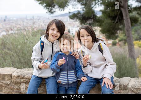 Bambini, ragazzi carini, giocando con fischio di argilla in ceramica in forma di uccello, souvenir dal parco Guell a Barcellona, Spagna Foto Stock