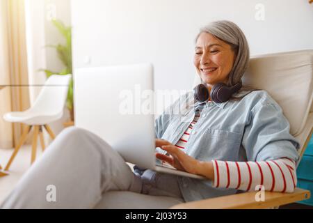 Donna sorridente che usa un moderno notebook a casa Foto Stock