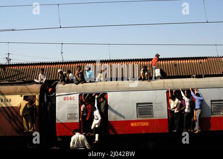 I pendolari indiani viaggiano sul tetto di un treno che effettua acrobazie su treni locali; 6 miliardi di pendolari viaggiano su treni locali del sobborgo occidentale di Mumbai. Foto Stock