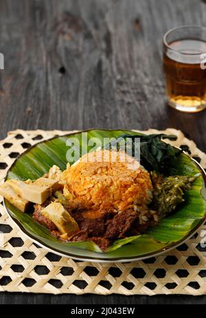 Nasi Padang servì con Rendang, giovane curry di Jackfruit, foglie di Cassava, e Sambal Hijau o Lado Mudo. Su tavola di legno Foto Stock