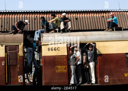 I pendolari indiani viaggiano sul tetto di un treno che effettua acrobazie su treni locali; 6 miliardi di pendolari viaggiano su treni locali del sobborgo occidentale di Mumbai. Foto Stock