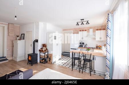 Interno di un luminoso monolocale con un camino in stile scandinavo in una casa privata, dove il soggiorno è combinato con la cucina. In un paese hous Foto Stock