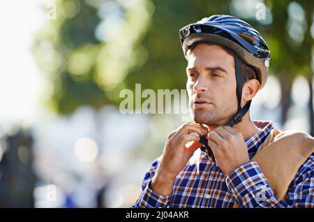 Con cinghie per la sicurezza. Scatto di un bel giovane che si prepara a fare un giro indossando un casco. Foto Stock