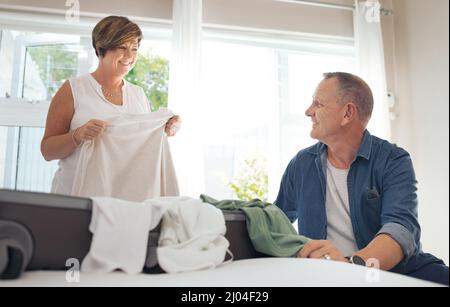 Mi aiuterai a piegare la lavanderia. Shot di una coppia matura pieghevole lavanderia insieme. Foto Stock