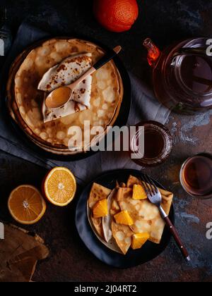 pancake fatti in casa in un piatto nero, tè Foto Stock