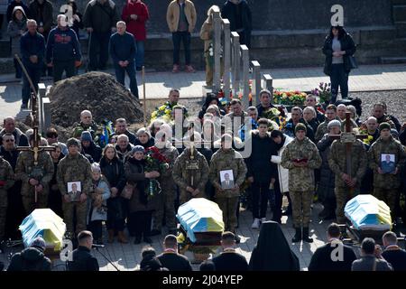 Non esclusiva: LVIV, UCRAINA - 15 MARZO 2022 - tre bare coperte di bandiere ucraine sono raffigurate durante le funerali militari dei militari Foto Stock