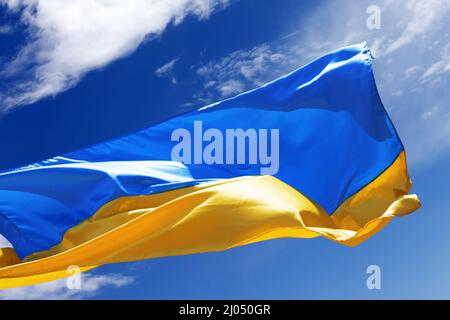 Bandiera della luce del sole dell'Ucraina che ondola su un cielo blu pacifico con le nuvole Foto Stock