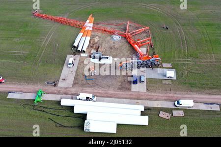 Elsterwerda, Germania. 16th Mar 2022. Una grande gru montata su camion si trova sul suo lato in un cantiere per una turbina eolica presso il parco eolico tra Elsterwerda e Stolzenhain (foto scattata dal drone). Durante lo smantellamento di tre turbine eoliche di 25 anni, la gru pesante da 500 tonnellate appartenente ad un'azienda di Amburgo, che era stata estesa a circa 100 metri, si è abbattuta. Nessuno è stato ferito nell'incidente. Credit: Veit Roesler/dpa/Alamy Live News Foto Stock