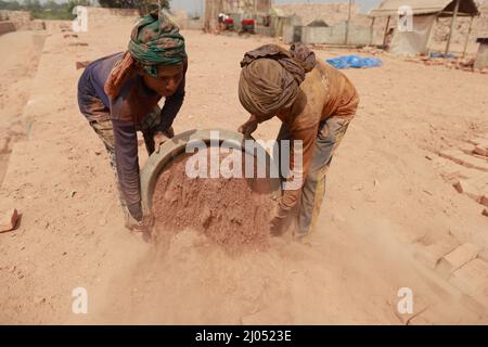 Gli uomini del Bangladesh lavorano in un campo di mattoni a Keraniganj, vicino a Dhaka, Bangladesh, 7 marzo 2022. Emissione di enorme quantità di elementi tossici da kil mattone Foto Stock