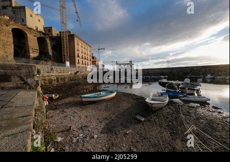 Pozzuoli, Italia. 16th Mar 2022. La darsena dei pescatori nel porto di Pozzuoli rimase quasi priva di acqua di mare per il bradicismo che in questo periodo si intensifica in tutta la zona dei campi Flegrei che si trova sulla più grande caldera d'Europa. Il bradicismo fa lievitare la terra e, in questo caso, le barche dei pescatori sono rimaste asciutte giacendo sulla terra. Credit: Independent Photo Agency/Alamy Live News Foto Stock