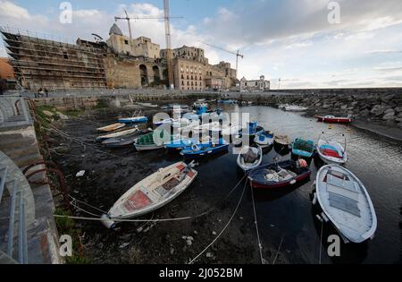 Pozzuoli, Italia. 16th Mar 2022. La darsena dei pescatori nel porto di Pozzuoli rimase quasi priva di acqua di mare per il bradicismo che in questo periodo si intensifica in tutta la zona dei campi Flegrei che si trova sulla più grande caldera d'Europa. Il bradicismo fa lievitare la terra e, in questo caso, le barche dei pescatori sono rimaste asciutte giacendo sulla terra. Credit: Independent Photo Agency/Alamy Live News Foto Stock