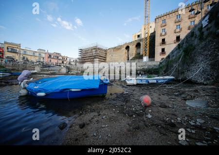 Pozzuoli, Italia. 16th Mar 2022. La darsena dei pescatori nel porto di Pozzuoli rimase quasi priva di acqua di mare per il bradicismo che in questo periodo si intensifica in tutta la zona dei campi Flegrei che si trova sulla più grande caldera d'Europa. Il bradicismo fa lievitare la terra e, in questo caso, le barche dei pescatori sono rimaste asciutte giacendo sulla terra. Credit: Independent Photo Agency/Alamy Live News Foto Stock