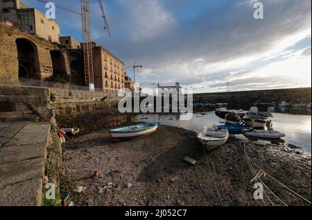 Pozzuoli, Italia. 16th Mar 2022. La darsena dei pescatori nel porto di Pozzuoli rimase quasi priva di acqua di mare per il bradicismo che in questo periodo si intensifica in tutta la zona dei campi Flegrei che si trova sulla più grande caldera d'Europa. Il bradicismo fa lievitare la terra e, in questo caso, le barche dei pescatori sono rimaste asciutte giacendo sulla terra. Credit: Independent Photo Agency/Alamy Live News Foto Stock