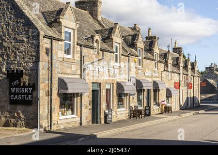 Luci serali sul Castello di Whisky e l'Highland Market in Main Street a Tomintoul, Moray, Scozia Regno Unito. Foto Stock