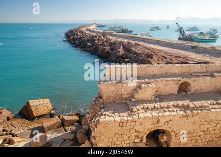Paesaggio con pescatori su frangiflutti di cemento nel porto di Alessandria, Egitto Foto Stock