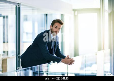 Impegnati nella vita aziendale. Scatto di un bel giovane uomo d'affari nel suo ufficio. Foto Stock