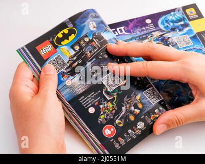 Tambov, Federazione russa - 21 dicembre 2021 Woman browsing Catalogo Lego su una pagina con set Lego Batman. Foto Stock