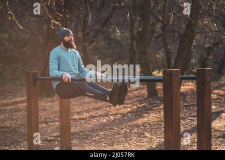 L'uomo ama fare esercizi sulle barre parallele del parco. Foto Stock