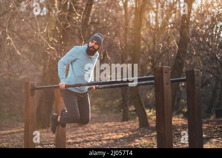 L'uomo ama fare esercizi sulle barre parallele del parco. Foto Stock