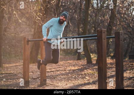 L'uomo ama fare esercizi sulle barre parallele del parco. Foto Stock