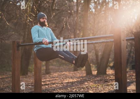 L'uomo ama fare esercizi sulle barre parallele del parco. Foto Stock