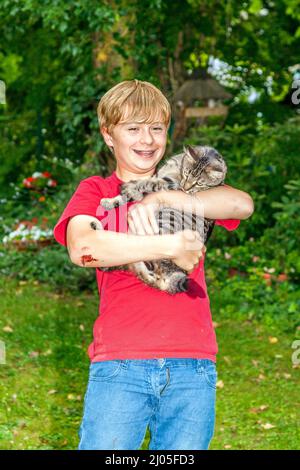 Carino boy tenendo il suo gatto nel braccio Foto Stock