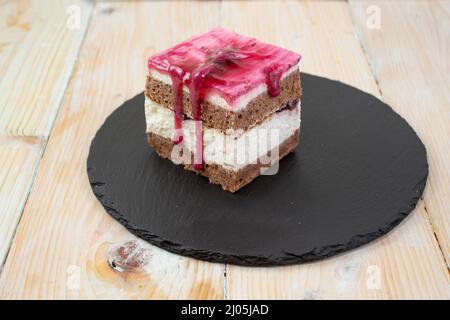 torta di frutta di bosco tagliata a cubetti, su una piastrella di pietra nera. Vista laterale Foto Stock