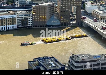 Londra, Inghilterra - Agosto 2021: Vista aerea di un rimorchiatore di chiatte pesanti caricato con contenitori di rifiuti e rifiuti sul Tamigi Foto Stock