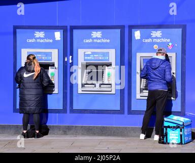 Le persone usano bancomat Halifax o bancomat automatico a Piccadilly, nel centro di Manchester, Regno Unito Foto Stock