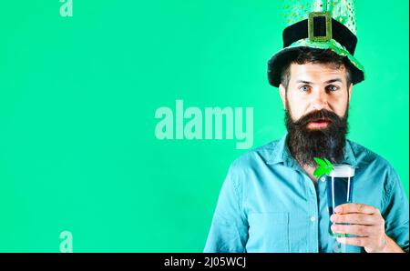 Festa del giorno di Patricks. Sorpreso uomo barbuto in cappello leprechaun con bicchiere di birra. Tradizione irlandese. Foto Stock