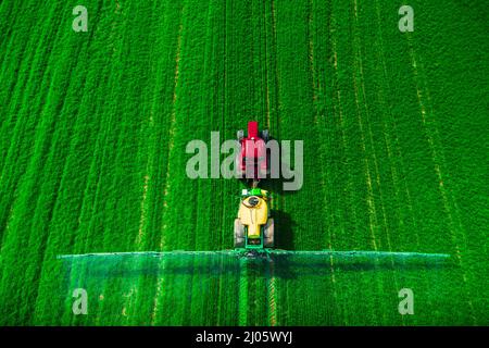 Vista aerea della trattrice agricola l'aratura e l'irrorazione sul campo. Foto Stock